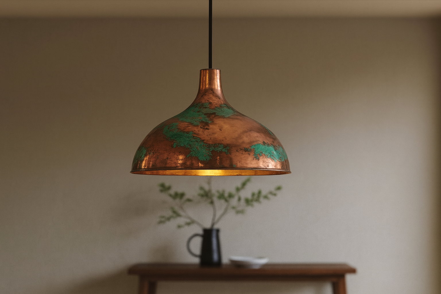Copper pendant light hanging above a wooden table with a blurred background